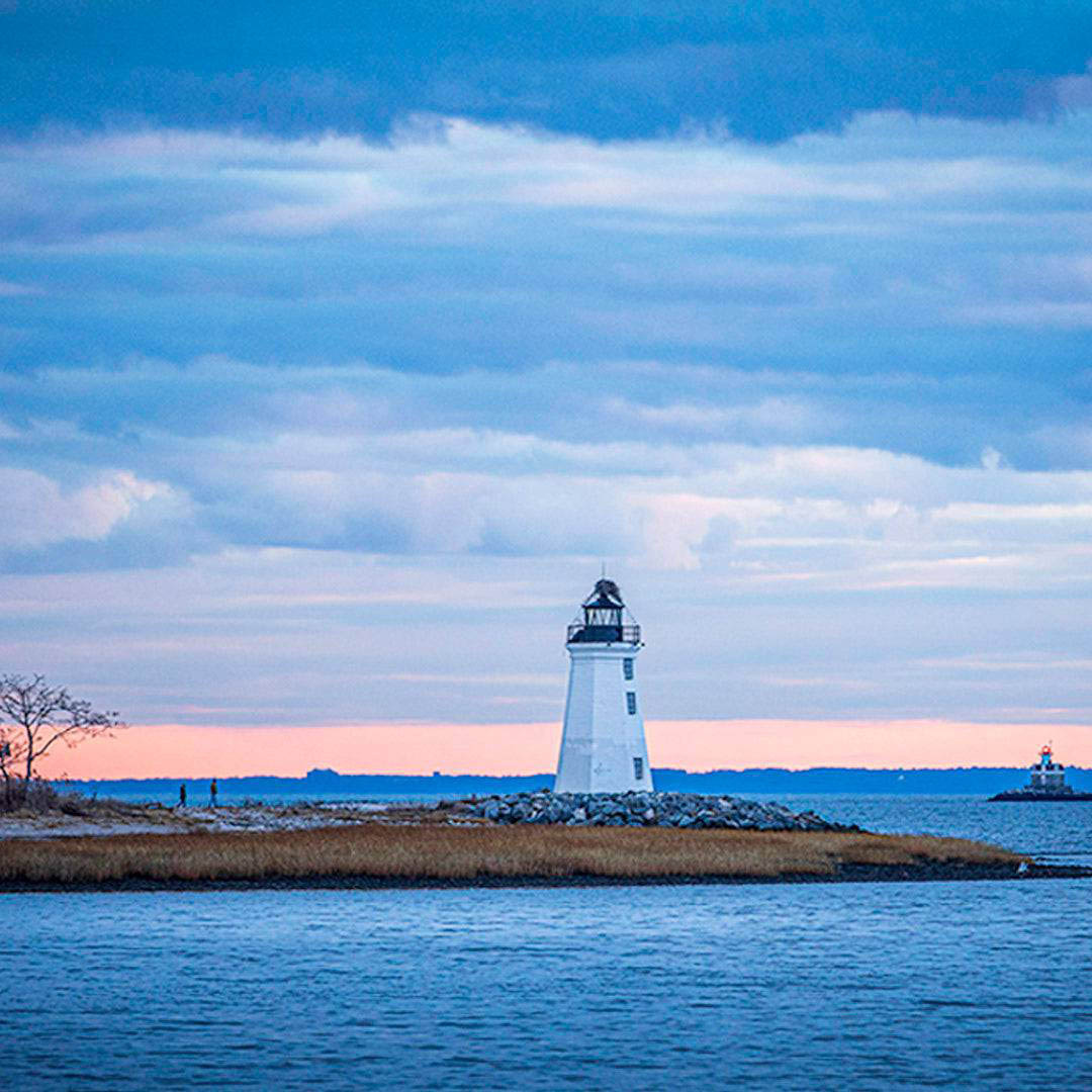 Lighthouse on a small island with a colorful sky