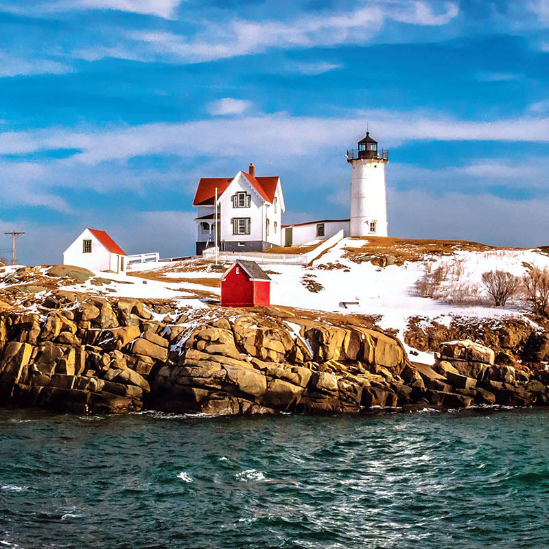 Lighthouse under blue skies with snowy bank