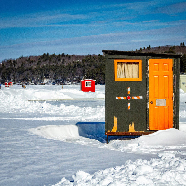 Small wooden shed with an orange door on a frozen lake
